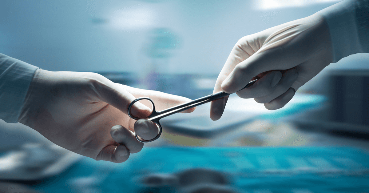 A surgical instrument being handed between gloved hands